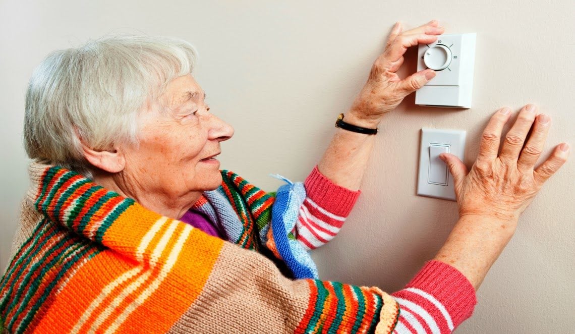 Senior Woman Adjusting Thermostat